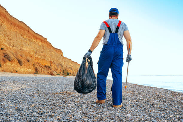istock Man volunteer collecting garbage on the beach with a reach extender stick 1280341317