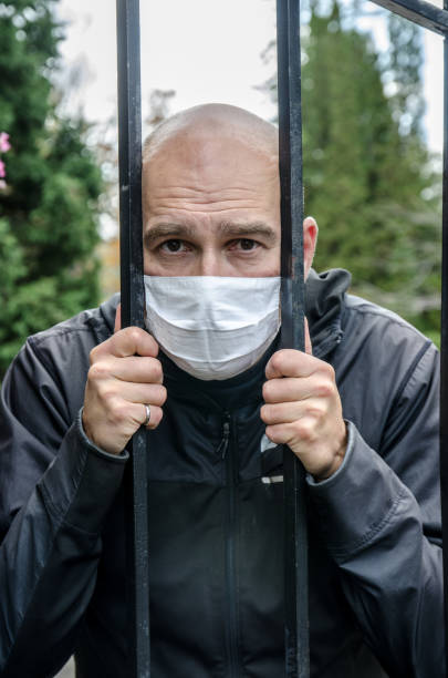 istock Man wearing face mask behind steel gate 1280342168