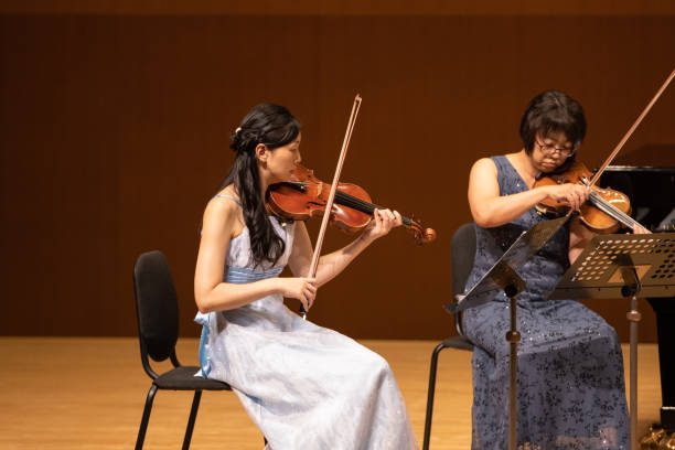 two female musicians playing violin at classical concert - violinista imagens e fotografias de stock