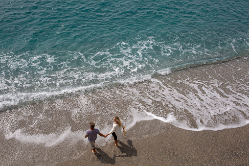 Aerial view of mature couple walking along beach