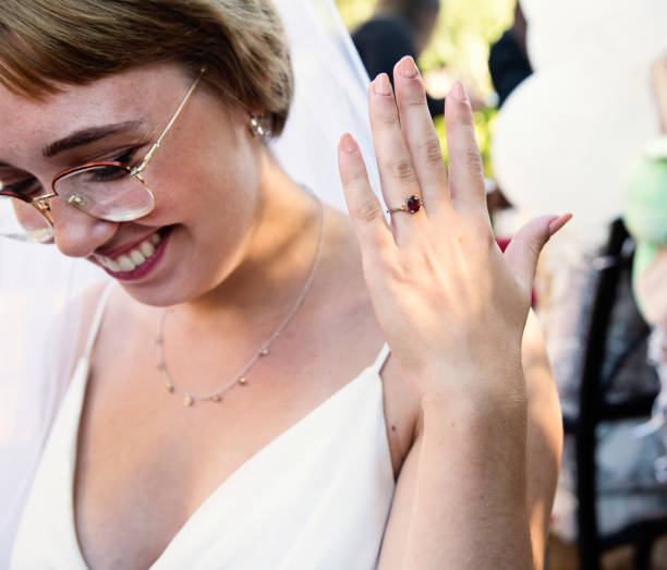 Millennial bride showing ring at wedding cocktail in backyard.