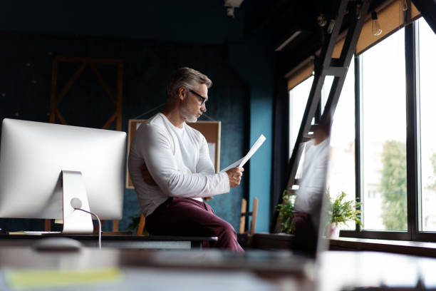 istock Casual Grey-haired Mature man reading paper in his office. 1280348826