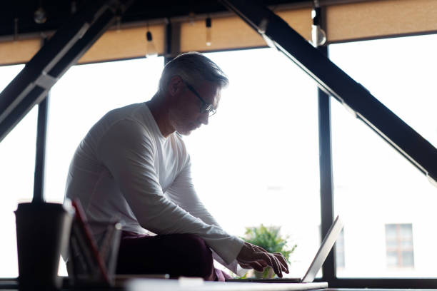 istock Casual Grey-haired Mature Male business executive using laptop in office. 1280348840