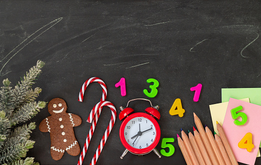 Christmas school holidays concept. Xmas sweets and school supplies on blackboard background top view