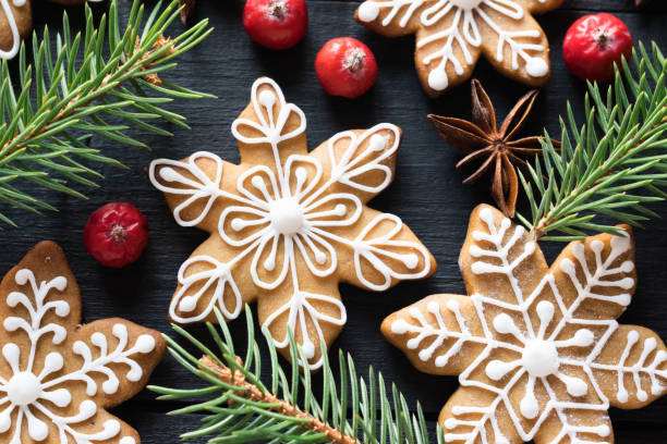 istock Gingerbread cookies snowflakes decorated with icing with fir-tree branches and berries on black wooden background. Close-up 1280354779