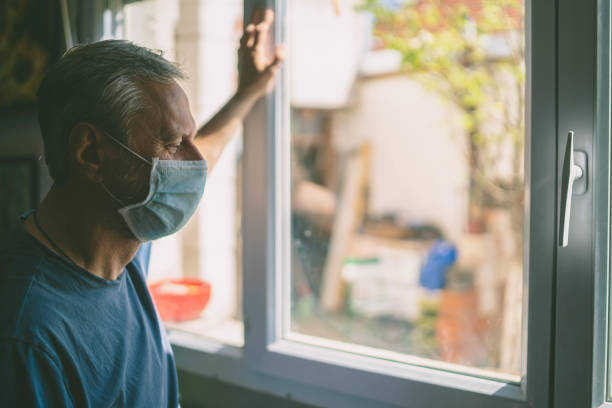 istock Mature man with mask looking out the window 1280354988
