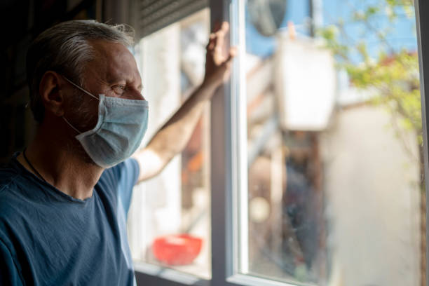 istock Mature man with mask looking out the window 1280355041