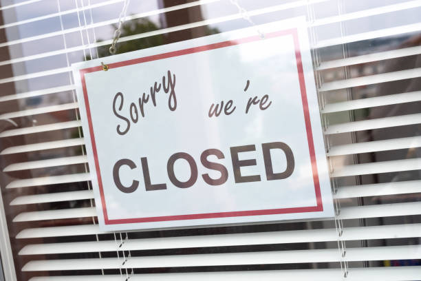 istock Closed sign hanging behind a store window 1280356246