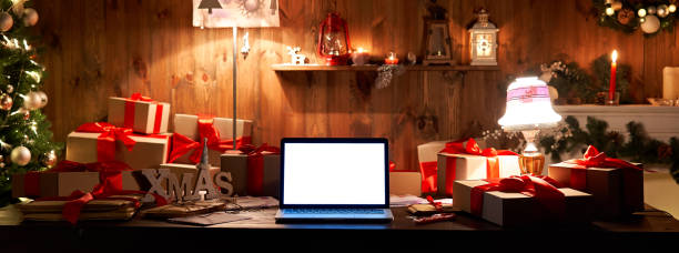 istock Laptop computer with white blank empty mock up screen on Merry Christmas table with presents gifts, decorated Xmas tree in Santa house background. Ecommerce website online shopping delivery, banner 1280356890