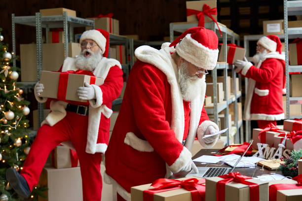 istock Many busy Santa Clauses packing gift boxes preparing fast xmas delivery. Three funny Santas walking in workshop warehouse in Merry Christmas rush delivering presents during holiday preparations. 1280356989