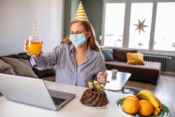 istock Young woman with face mask at home having a celebration on a video call 1280358517
