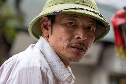 Hanoi, Vietnam - march 01, 2020 : Vietnamese man in hat on the street in the old town of Hanoi, Vietnam