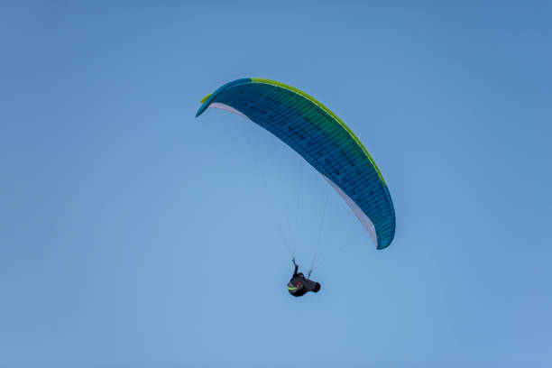 istock Paragliders with multi-colored parachutes fly high in the clear blue sky over steep cliffs. Parachuting, adrenalitis, love of height, risk, freedom of action. Desire to be able to fly 1280361797