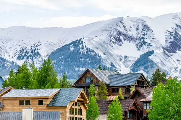 Photo of Mount Crested Butte, Colorado village in summer morning with hilldside houses on hills and Aspen green trees closeup
