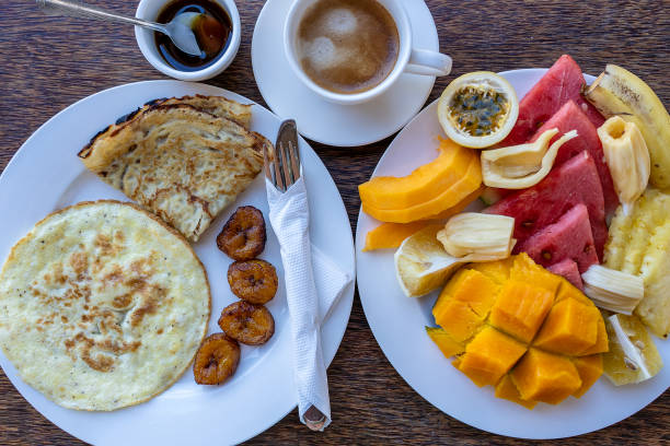 Tropical breakfast of fruit, coffee and fried eggs and banana pancake in hotel restaurant, island Zanzibar, Tanzania, Africa, close up, top view