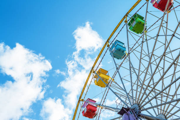 istock Multi-colored Ferris wheel booths against a blue sky with clouds 1280363507