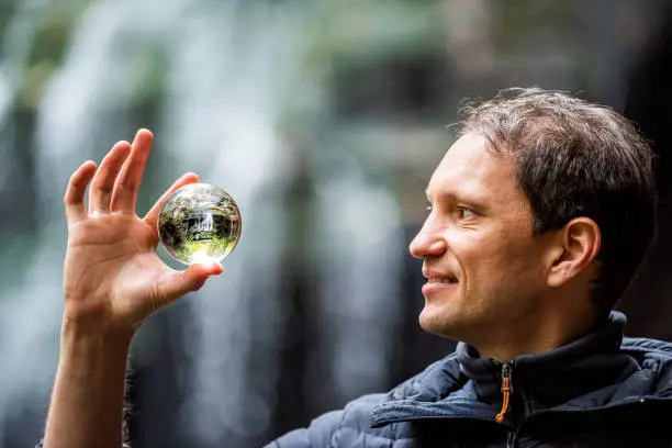 Photo of Blackwater Falls famous Elakala waterfall closeup of man holding crystal ball reflection in State Park in West Virginia during autumn fall season