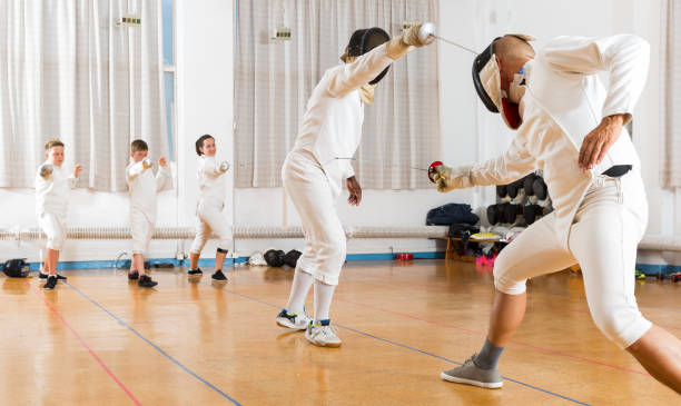 istock Adults and teens wearing fencing uniform practicing with foil 1280363939