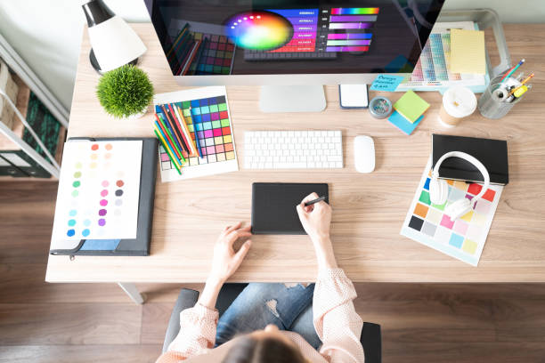 Workspace of a graphic designer Top view of a woman using a graphic tablet and doing some design work in her workspace with many color palettes and swatches graphic designer photos stock pictures, royalty-free photos & images