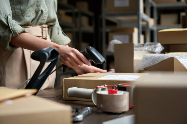 istock Female seller online store worker holding scanner scanning parcel bar code packing e commerce post shipping box preparing online retail shop order in dropshipping delivery service warehouse. 1280365986
