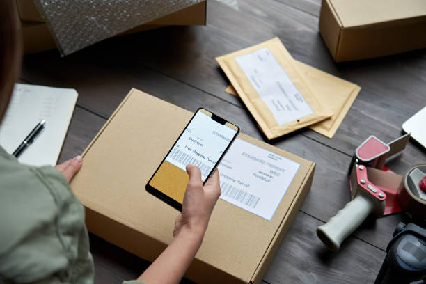 Female warehouse worker, seller, dropshipping small business owner holding phone scanning retail package postal parcel barcode on ecommerce shipping box label on smartphone using mobile app, close up. mujer trabajadora de almacén, vendedor, dropshipping propietario de pequeñas empresas que sostiene el teléfono de escaneo de paquetes de venta al por menor código de barras de paquete postal en la etiqueta de la caja de envío de comercio electrónico