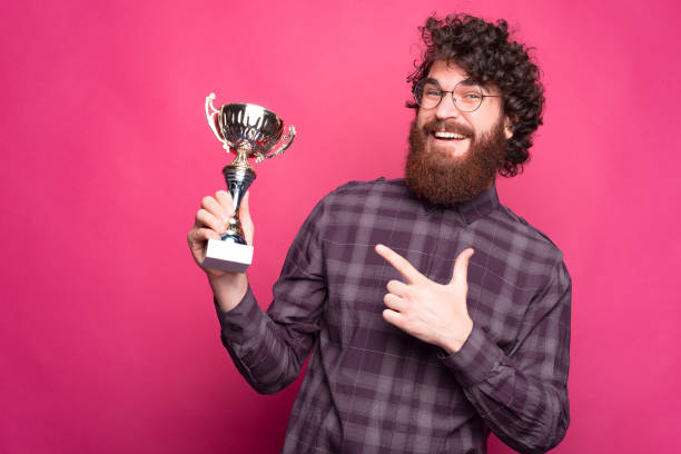 istock Joyful young man is holding a cup and pointing at it smiling at the camera 1280367748