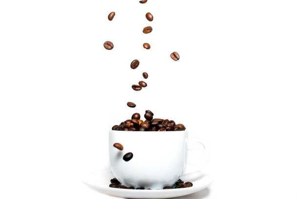 istock Roasted coffee beans falling into a coffee cup on a saucer with a white background, close-up, coffee wallpaper 1280367935