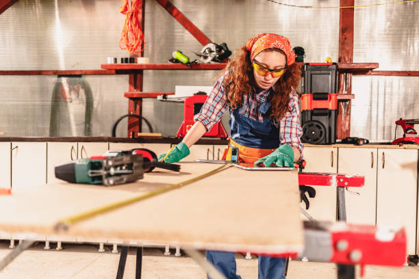 istock Young female carpenter measures the board with a ruler . 1280369529