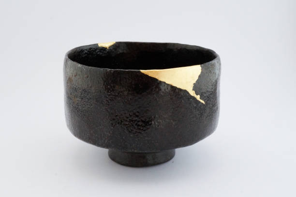 istock Antique broken Japanese raku black bowl repaired with gold kintsugi technique 1280370238