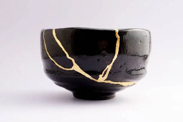 Photo of Antique broken Japanese raku black bowl repaired with gold kintsugi technique