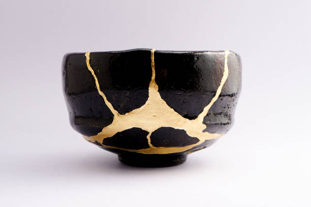 istock Antique broken Japanese raku black bowl repaired with gold kintsugi technique 1280370372