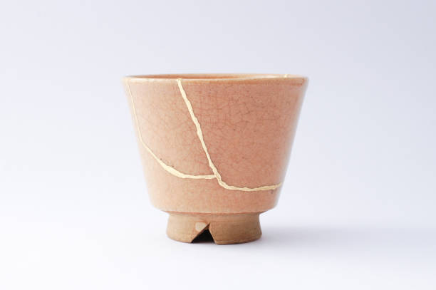 Antique broken Japanese beige sake cup repaired with gold kintsugi technique