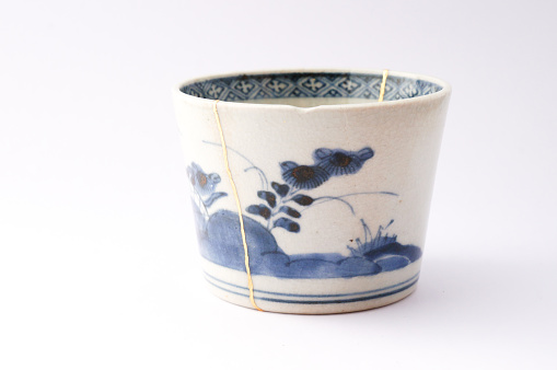 Kintsugi blue and white cup. Gold cracks restoration on old Japanese pottery restored with the antique Kintsugi restoration technique. The beauty of imperfections. japanese pottery repair gold. japanese art of repairing cracks with gold. japanese art of fixing broken pottery