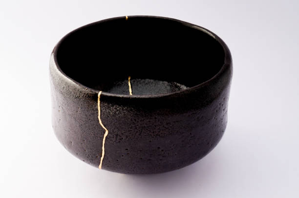 istock Antique broken Japanese raku black bowl repaired with gold kintsugi technique 1280370451