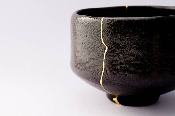 istock Antique broken Japanese raku black bowl repaired with gold kintsugi technique 1280370452