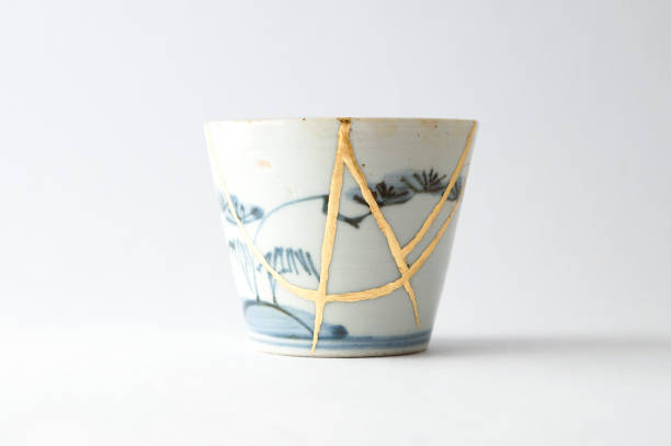 Antique broken Japanese soba cup repaired with gold kintsugi technique stock photo