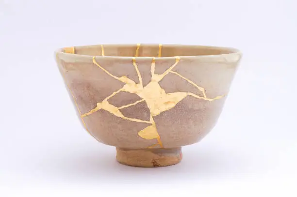 Photo of Antique broken Japanese beige bowl repaired with gold kintsugi technique