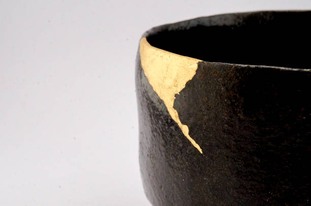 istock Antique broken Japanese black raku bowl repaired with gold kintsugi technique 1280373114