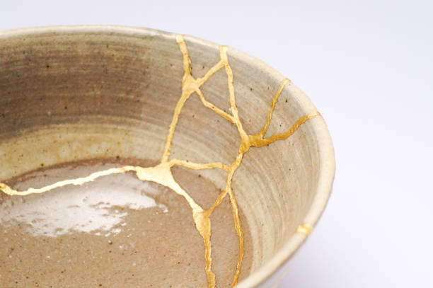 Antique broken Japanese beige bowl repaired with gold kintsugi technique Kintsugi beige bowl. Gold cracks restoration on old Japanese pottery restored with the antique Kintsugi restoration technique. The beauty of imperfections. japanese pottery repair gold. japanese art of repairing cracks with gold. japanese art of fixing broken pottery 50th anniversary photos stock pictures, royalty-free photos & images