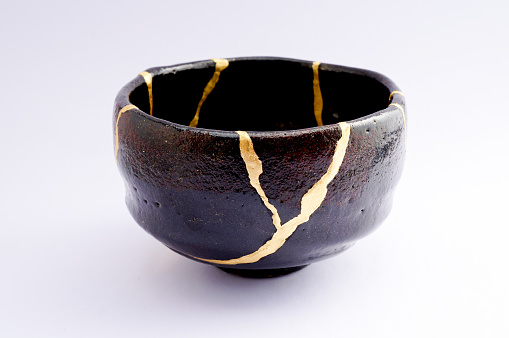 Antique broken Japanese black raku bowl repaired with gold kintsugi technique