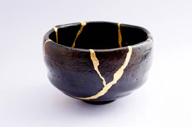 Photo of Antique broken Japanese black raku bowl repaired with gold kintsugi technique