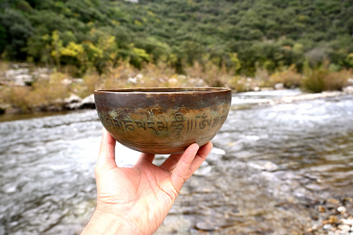 A man is holding a copper tibetan singing bowl.
