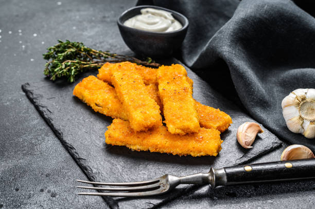 istock Oven baked crumbed fish sticks made from white fish.  Black background. Top view 1280376541