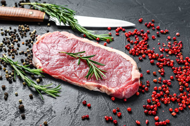 istock Raw striploin steak or strip New York with herbs. Black background. Top view 1280378796