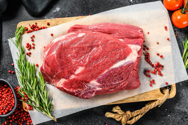 istock Raw Round beef cut on a cutting board. Black background. Top view 1280378824