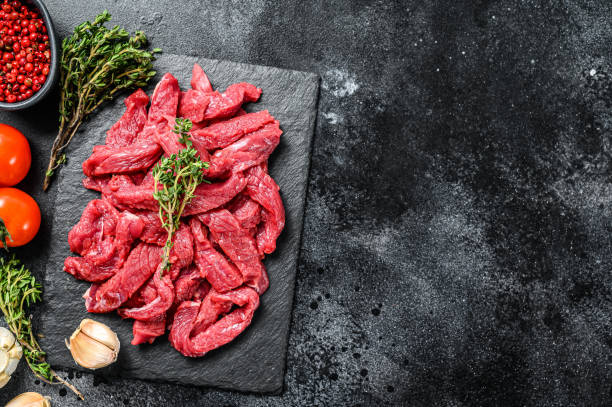 istock Raw beef Stroganoff meat. Black background. Top view. Copy space 1280379116