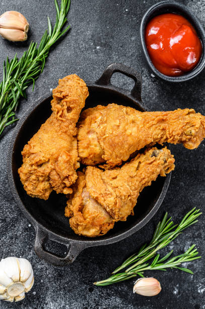 istock Fried crispy chicken legs, drumstick in a pan. Black background. Top view 1280380374