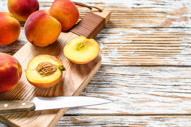 istock Fresh Peaches, organic fruit on the chopping Board. White wooden background. Top view. Copy space. 1280380381