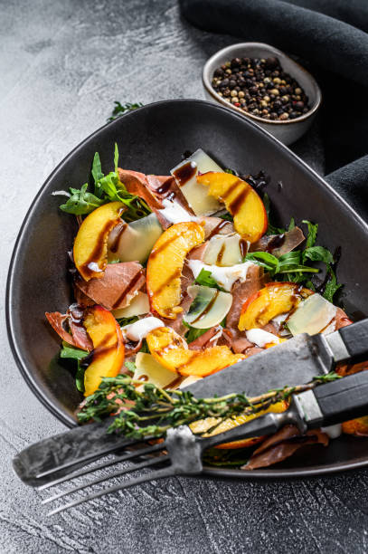istock Salad with jamon Iberico, arugula, peach and Parmesan. Gray background. Top view 1280382768