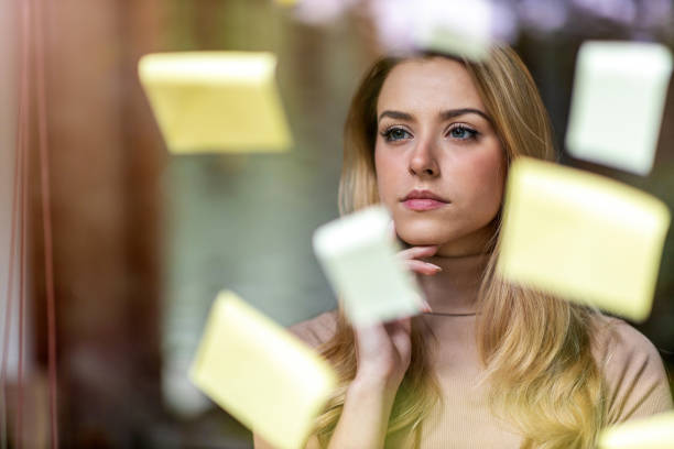 istock Young businesswoman brainstorming with notes on a glass wall in an office 1280383733
